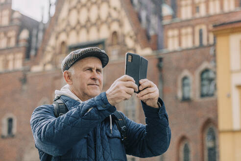Älterer Mann fotografiert mit seinem Smartphone - VSNF00712