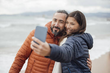Ein glückliches Paar hält seine Erinnerungen an den Strand mit einem Selfie mit dem Smartphone fest - JOSEF18472