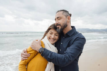 Smiling mature man hugging woman at beach - JOSEF18487