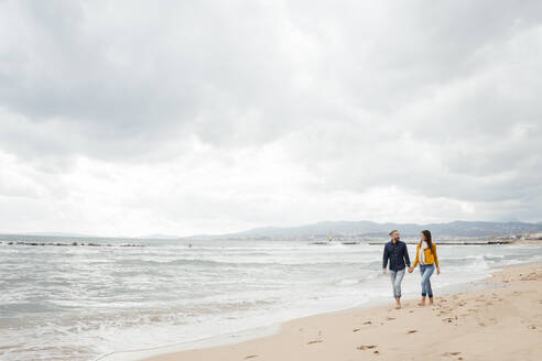 Man and woman walking together on coastline at beach - JOSEF18493