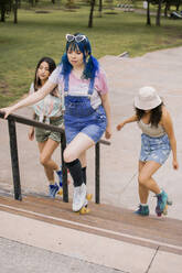 Freunde ziehen gemeinsam auf einer Treppe im Park nach oben - EGCF00086
