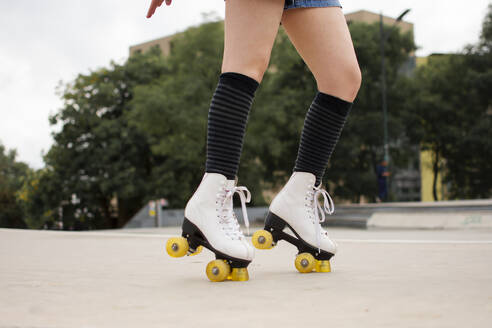 Young woman roller skating on footpath in park - EGCF00092