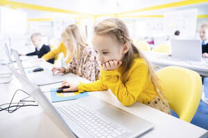Blondes Schulmädchen lernt im Computerkurs am Laptop - NJAF00325
