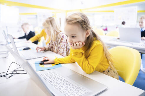 Blond schoolgirl learning through laptop in computer class - NJAF00325