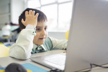 Schoolboy leaning on elbow using laptop in computer class - NJAF00332