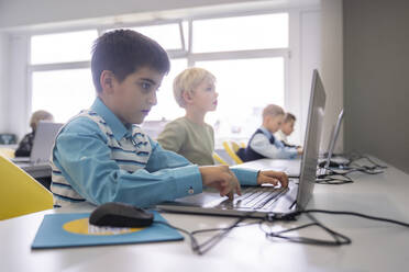 Junge beim E-Learning mit Laptop am Schreibtisch in der Schule - NJAF00338