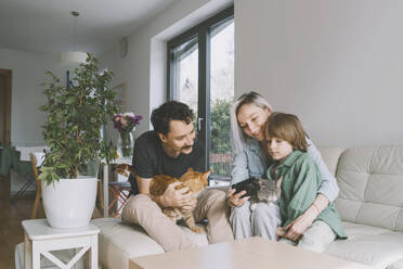Glückliche Familie mit Katzen, die in die Kamera schauen - NDEF00541