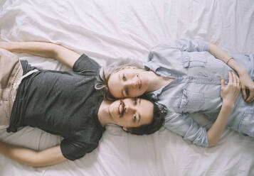 Happy couple lying on back together at home - NDEF00551