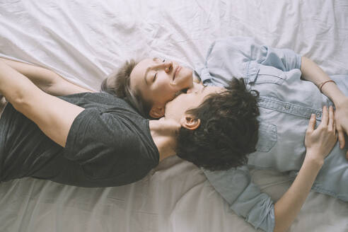 Mann küsst Frau auf dem Bett liegend zu Hause - NDEF00554