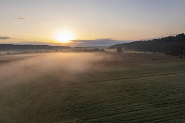 Germany, Bavaria, Aerial view of agricultural field at foggy sunrise - RUEF04041