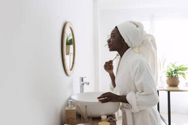 Junge Frau benutzt Jadewalze im Badezimmer zu Hause - AAZF00312