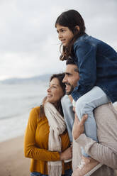 Lächelnde Frau mit Mann, der seine Tochter auf den Schultern trägt, am Strand - JOSEF18497
