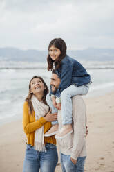 Happy woman with family enjoying at beach - JOSEF18517