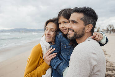 Lächelnde Frau mit Mann und Tochter, die sich am Strand umarmen - JOSEF18521