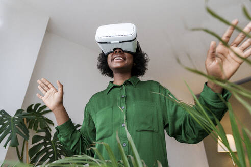 Glückliche Frau gestikuliert im Virtual-Reality-Simulator - AAZF00368