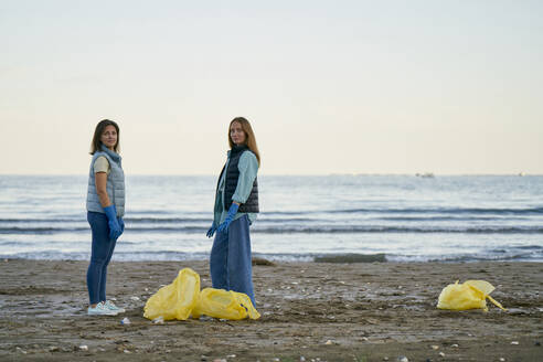 Environmentalists standing near plastic bags at beach - ANNF00103