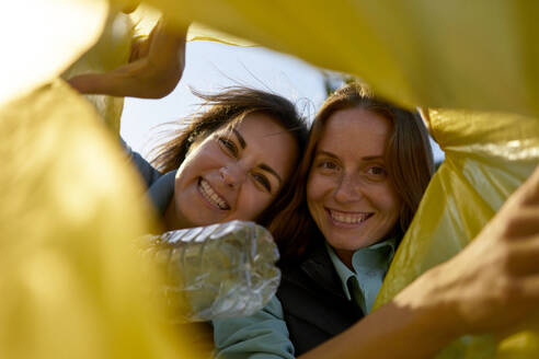 Happy volunteers looking in plastic garbage bag - ANNF00118