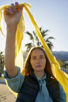 Volunteer holding yellow plastic bag at beach - ANNF00127
