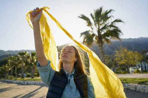 Activist with eyes closed holding plastic bag at beach - ANNF00128