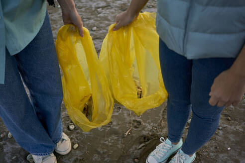 Activists holding plastic bags with garbage at beach - ANNF00130