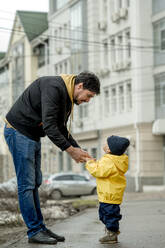 Vater hält die Hand seines Sohnes auf dem Fußweg - ANAF01240