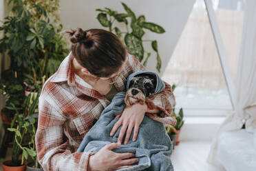 Woman embracing dog wrapped in towel - YTF00754