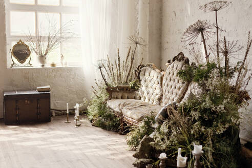 Mit Trockenblumen und Pflanzen dekoriertes Vintage-Sofa in einer Loftwohnung - ONAF00500