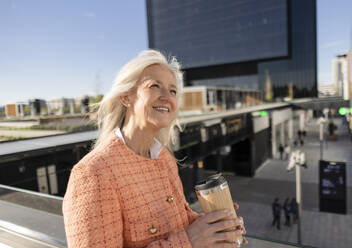 Smiling mature businesswoman holding reusable coffee cup - JCCMF10298