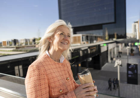 Lächelnde reife Geschäftsfrau mit wiederverwendbarem Kaffeebecher - JCCMF10298