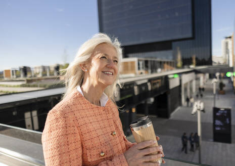 Smiling mature businesswoman holding reusable coffee cup - JCCMF10298