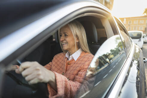 Smiling mature woman driving car - JCCMF10320