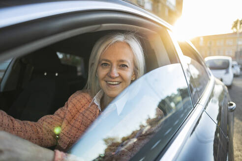 Lächelnde Frau beim Autofahren an einem sonnigen Tag - JCCMF10321