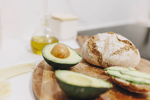 Avocado und Brot in Scheiben geschnitten auf dem Schneidebrett - MRRF02595