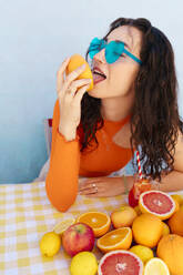 Frau mit Sonnenbrille leckt an Zitrusfrüchten - EGHF00760