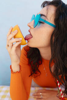 Frau mit herzförmiger Sonnenbrille leckt Grapefruit - EGHF00761