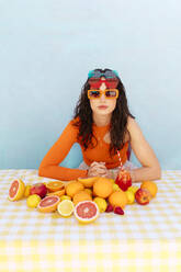 Frau mit Sonnenbrille und verschiedenen Zitrusfrüchten auf dem Tisch - EGHF00762