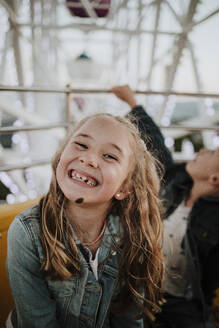 Glückliches Mädchen genießt die Fahrt mit dem Riesenrad im Vergnügungspark - GMLF01417