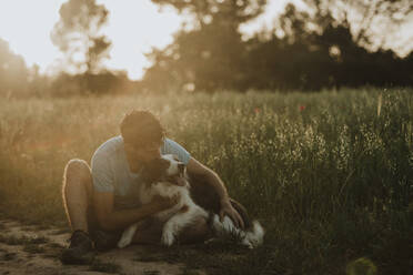 Mann küsst Border Collie Hund auf einem Feld - GMLF01425