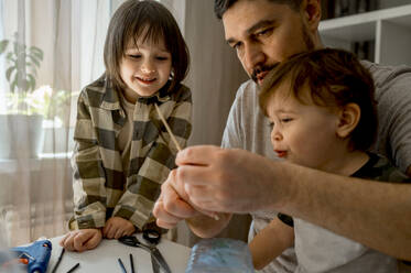 Father and sons making car from plastic bottle at home - ANAF01254