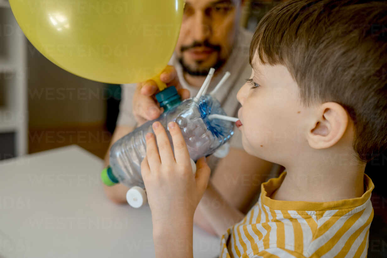 https://us.images.westend61.de/0001816682pw/boy-blowing-balloon-from-plastic-car-bottle-at-home-ANAF01263.jpg