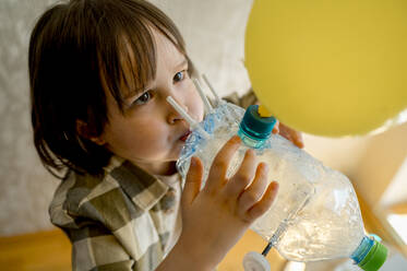 Junge bläst Luftballon durch Plastikflasche Auto zu Hause - ANAF01265