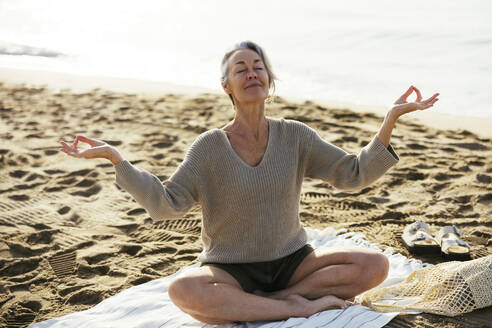 Mature woman meditating at beach - EBSF03220