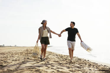 Mann und Frau halten sich an den Händen und gehen am Strand spazieren - EBSF03232