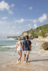 Paar hält sich an den Händen und geht am Strand spazieren - IKF00167