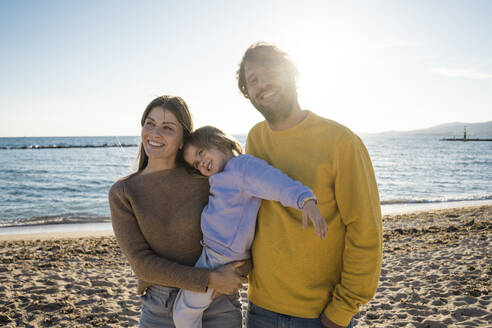 Vater und Mutter stehen mit ihrer Tochter am Strand - JOSEF18574
