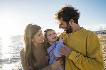 Smiling daughter having fun with father and mother at beach - JOSEF18589