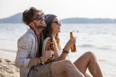 Happy couple having beer at beach - IKF00189