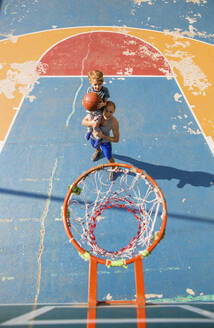 Sohn und Vater spielen Basketball auf dem Sportplatz - IKF00199