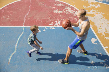 Vater und Sohn spielen Basketball auf dem Platz - IKF00201