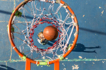 Son throwing basketball standing under hoop - IKF00204